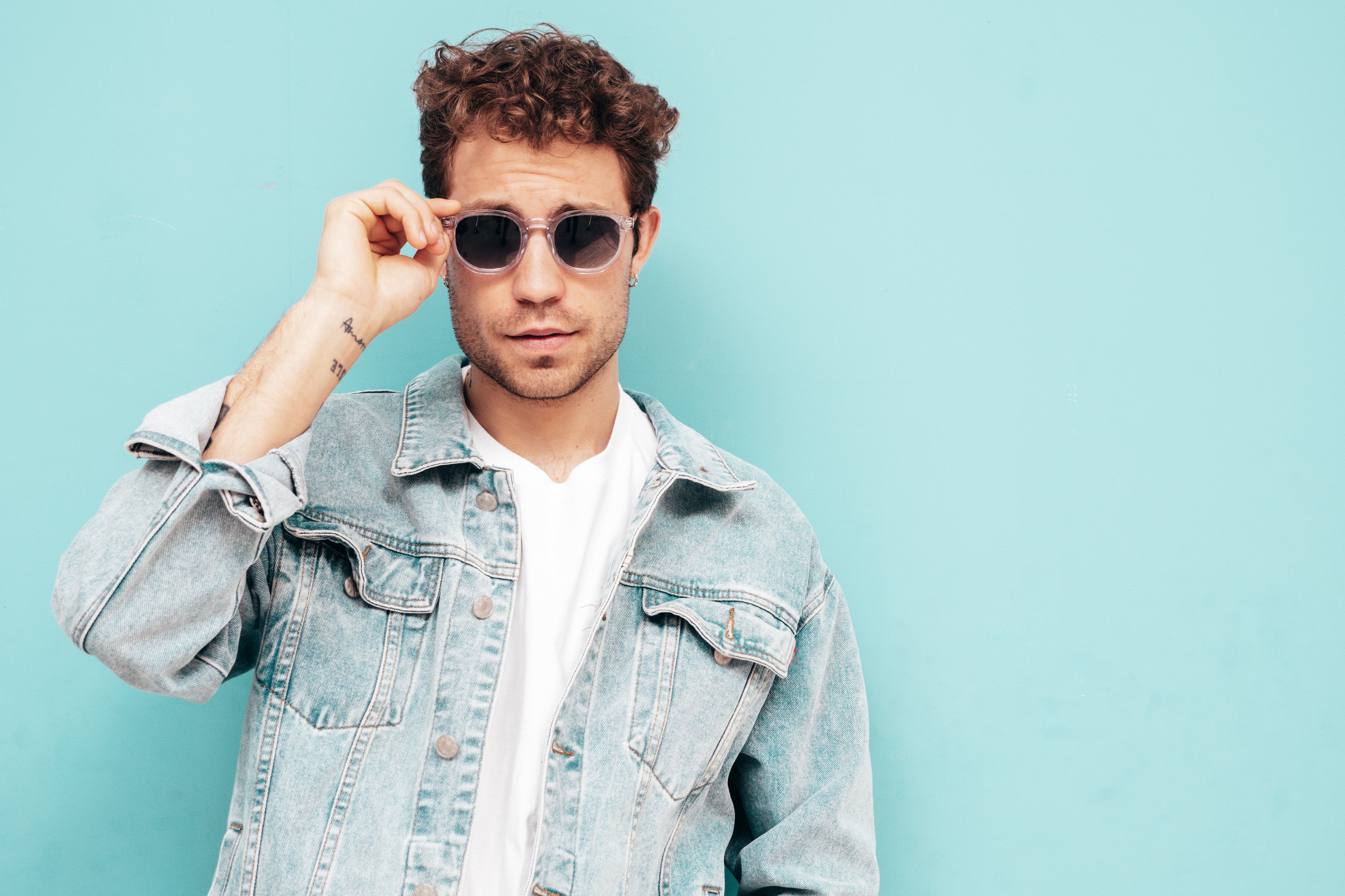files/retrato-de-guapo-modelo-lambersexual-con-estilo-hipster-con-peinado-rizado-hombre-sexy-vestido-con-chaqueta-de-jeans-hombre-de-moda-aislado-en-la-pared-azul-en-estudio-en-gafas-de-sol.jpg