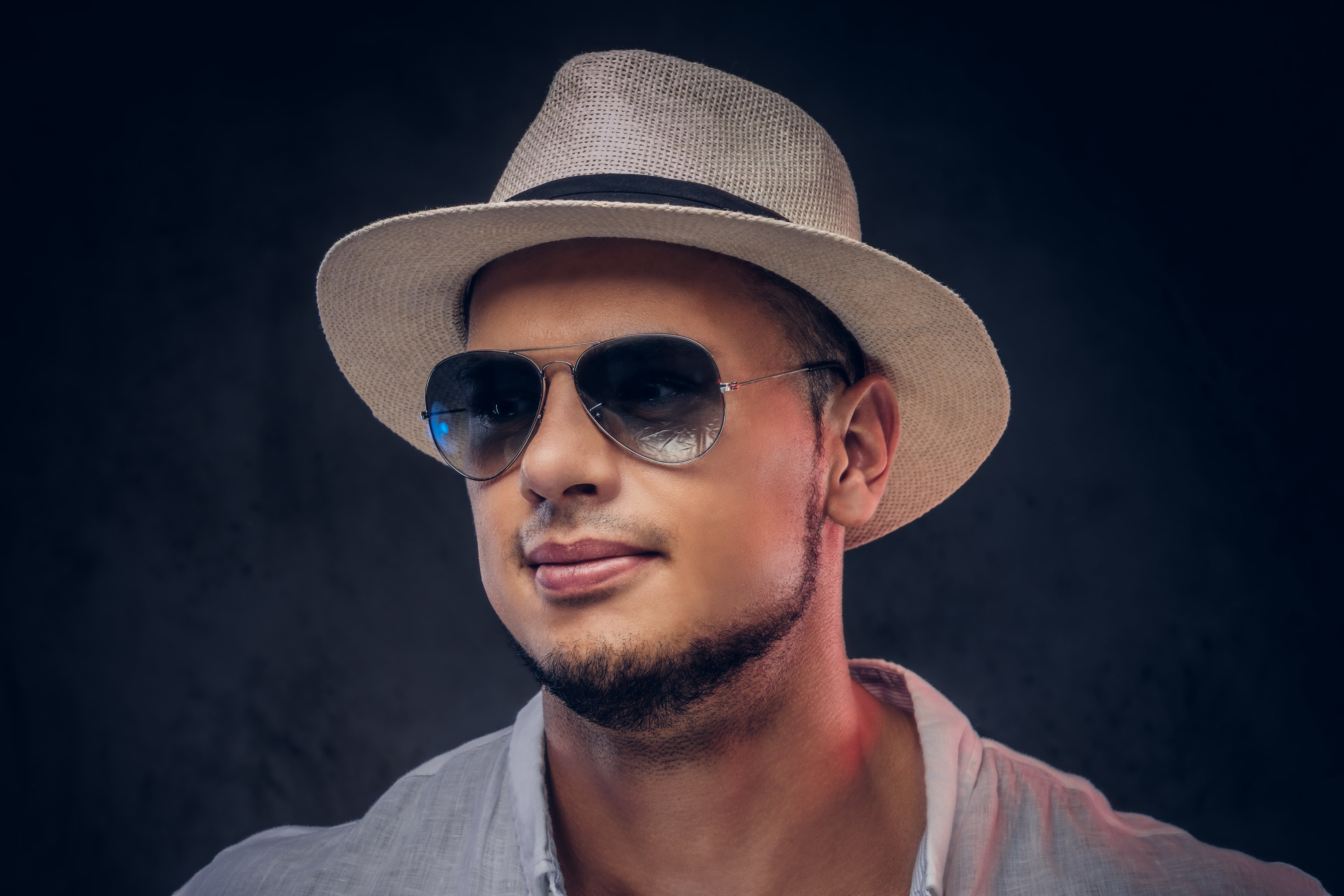 files/retrato-de-primer-plano-de-un-apuesto-hombre-barbudo-de-moda-con-una-camisa-blanca-sombrero-de-panama-y-gafas-de-sol-aislado-sobre-fondo-oscuro.jpg